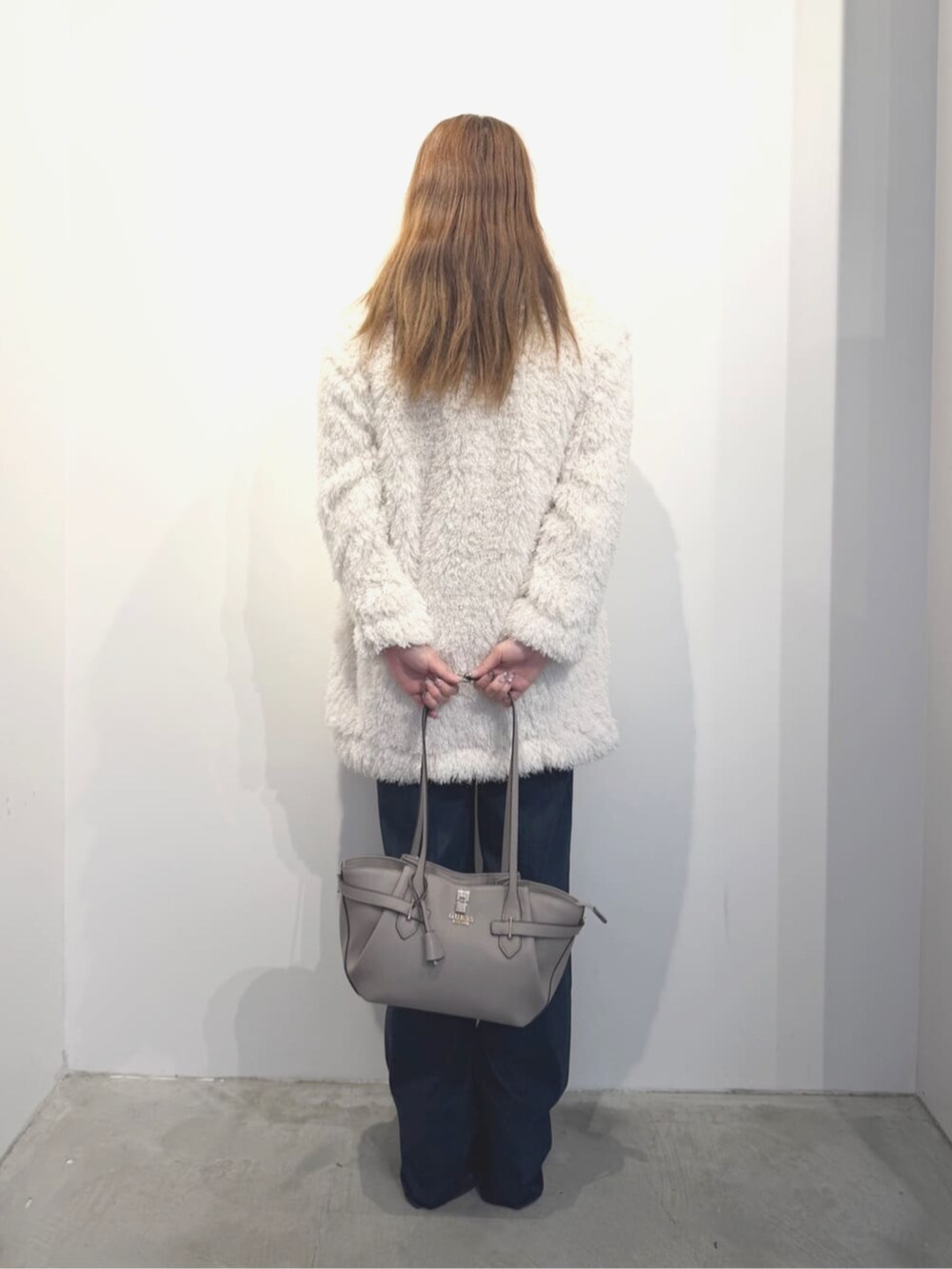 ホワイト系のカーディガン/ボレロ、ベージュ系のトートバッグ、ブルー系のデニムパンツを着用したレディースの春コーディネートの2枚目の写真