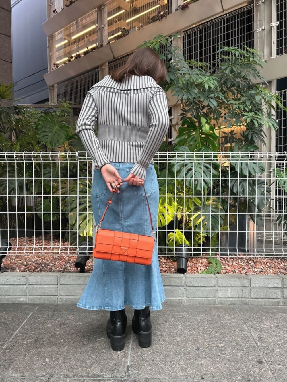 グレー系のカーディガン/ボレロ、ブルー系のデニムスカート、オレンジ系のショルダーバッグを着用したレディースの秋コーディネートの2枚目の写真