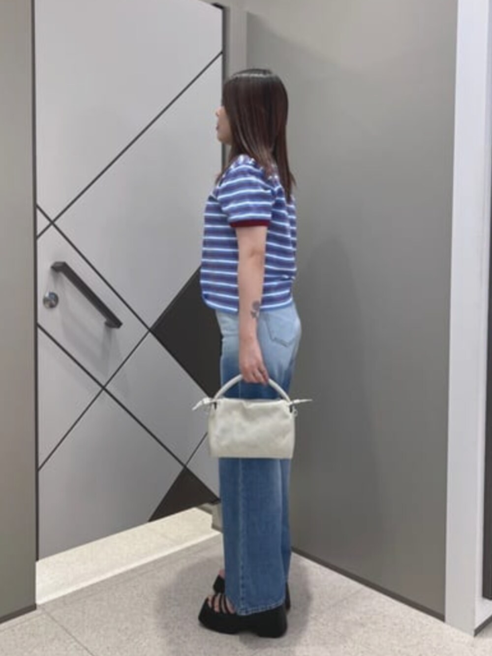 ブルー系のポロシャツ、ベージュ系のショルダーバッグ、ブルー系のデニムパンツを着用したレディースの夏コーディネートの3枚目の写真