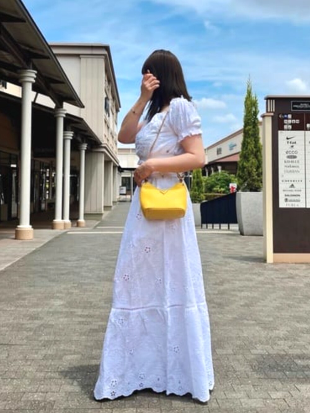 イエロー系のハンドバッグを着用したレディースの夏コーディネートの3枚目の写真