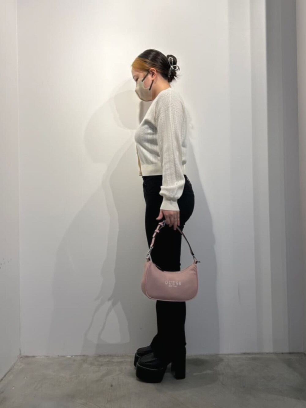 ピンク系のショルダーバッグ、ブラック系のデニムパンツ、ブラック系のカーディガン/ボレロを着用したレディースの冬コーディネートの3枚目の写真