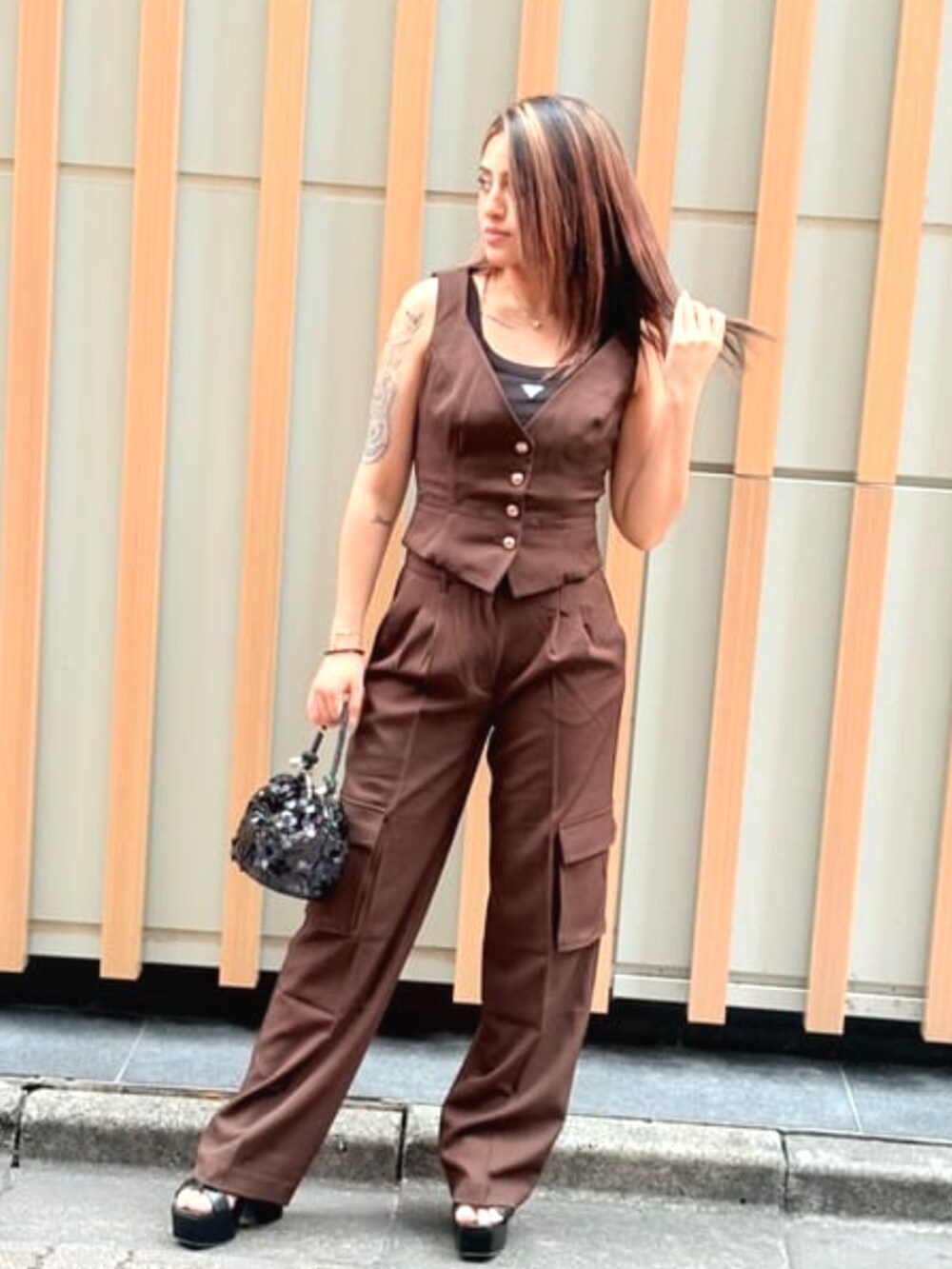 ブラウン系のベスト、ブラウン系のカーゴパンツ、ブラック系のショルダーバッグを着用したレディースの夏コーディネートの3枚目の写真