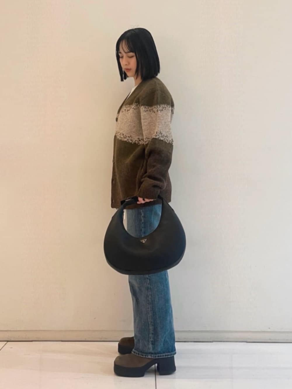 ブルー系のデニムパンツ、ブラック系のハンドバッグ、ホワイト系のTシャツ/カットソーを着用したレディースの春コーディネートの3枚目の写真