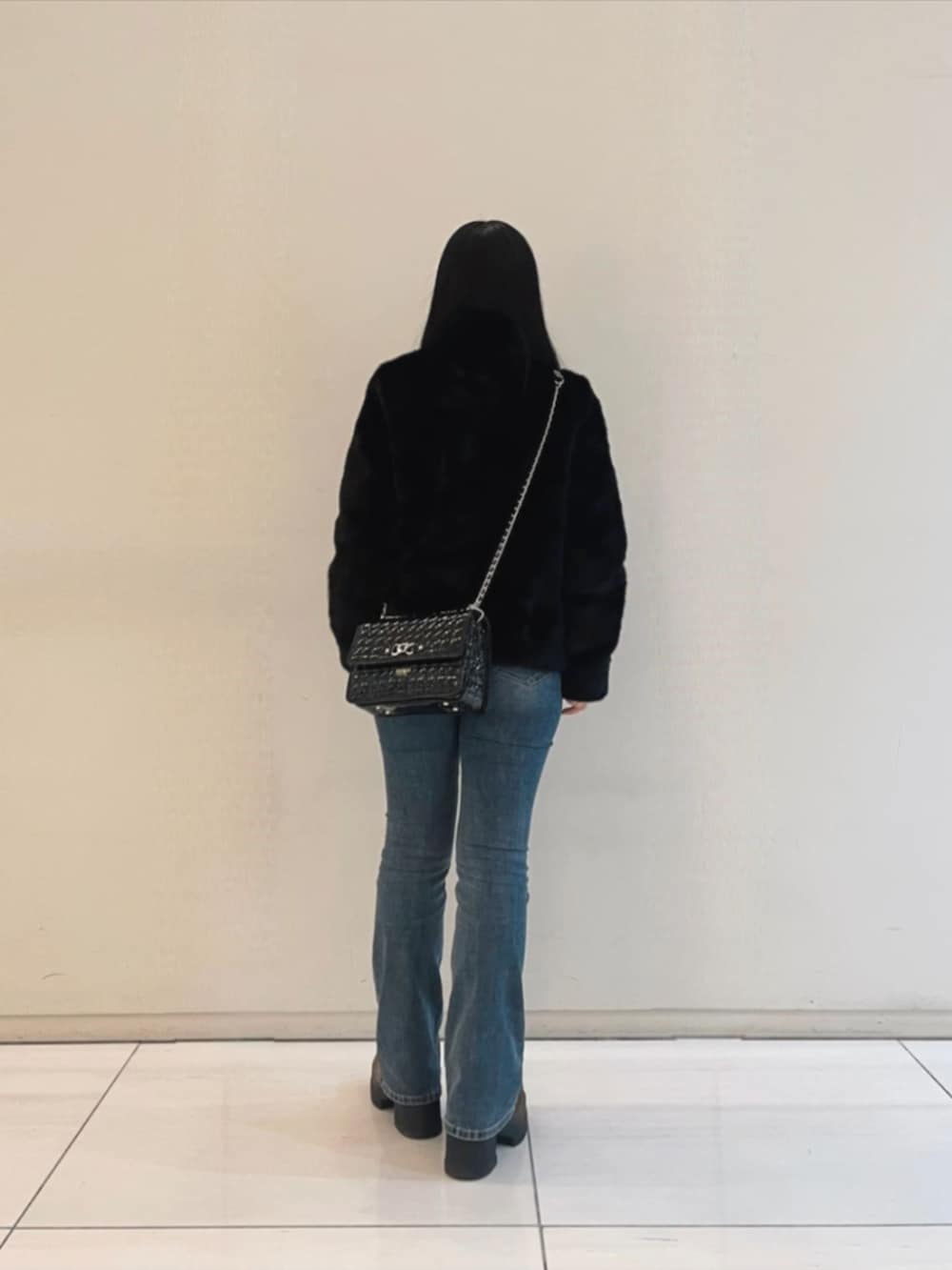 ブルー系のデニムパンツ、ホワイト系のスウェット、ブラック系のショルダーバッグを着用したレディースの冬コーディネートの2枚目の写真