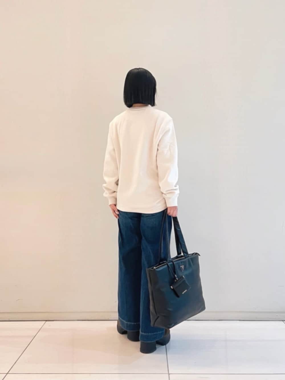 ホワイト系のスウェット、ブラック系のトートバッグを着用したレディースの冬コーディネートの2枚目の写真