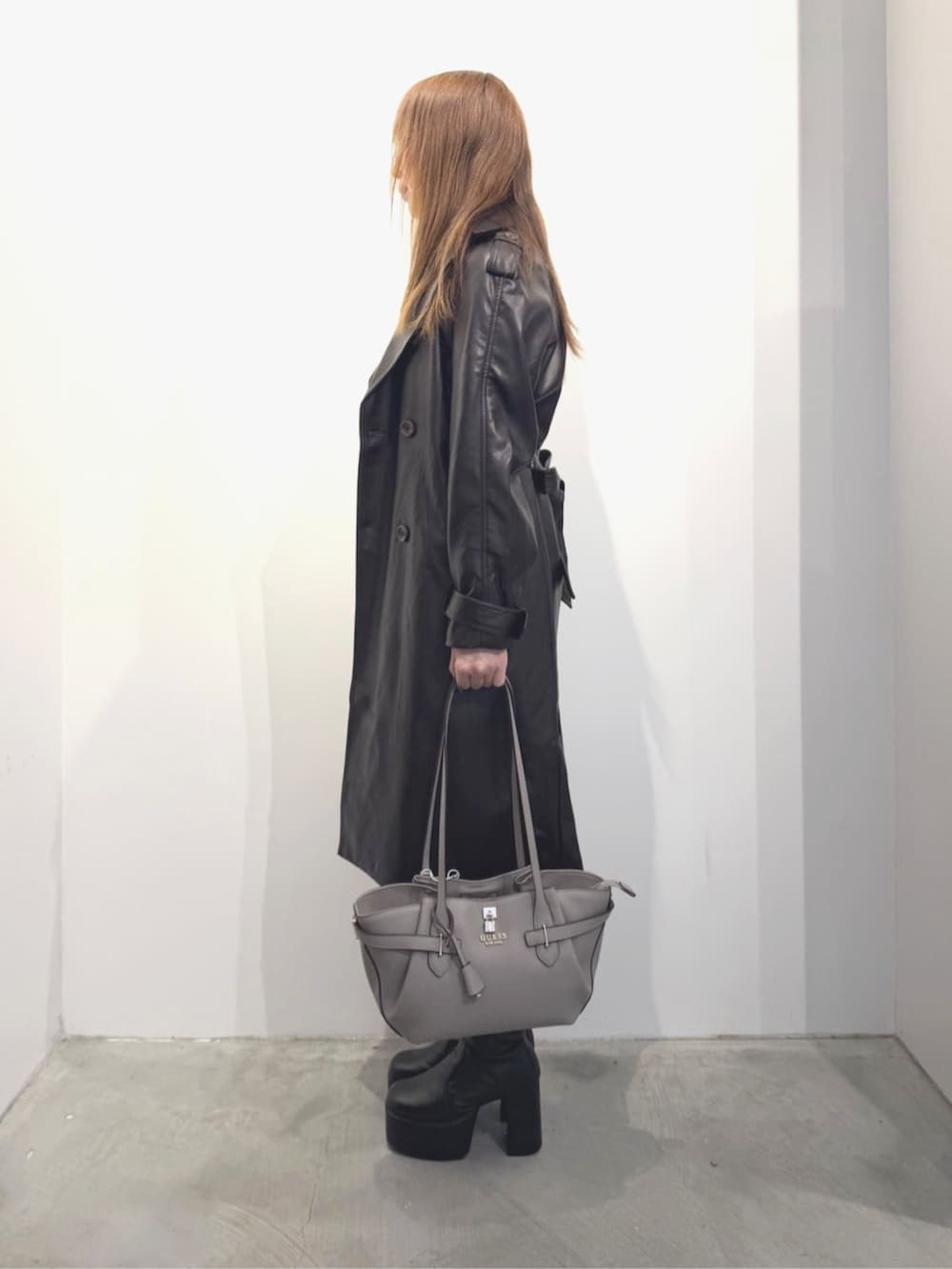 ブラウン系のトレンチコート、ベージュ系のトートバッグ、ブラウン系のワンピースを着用したレディースの春コーディネートの2枚目の写真