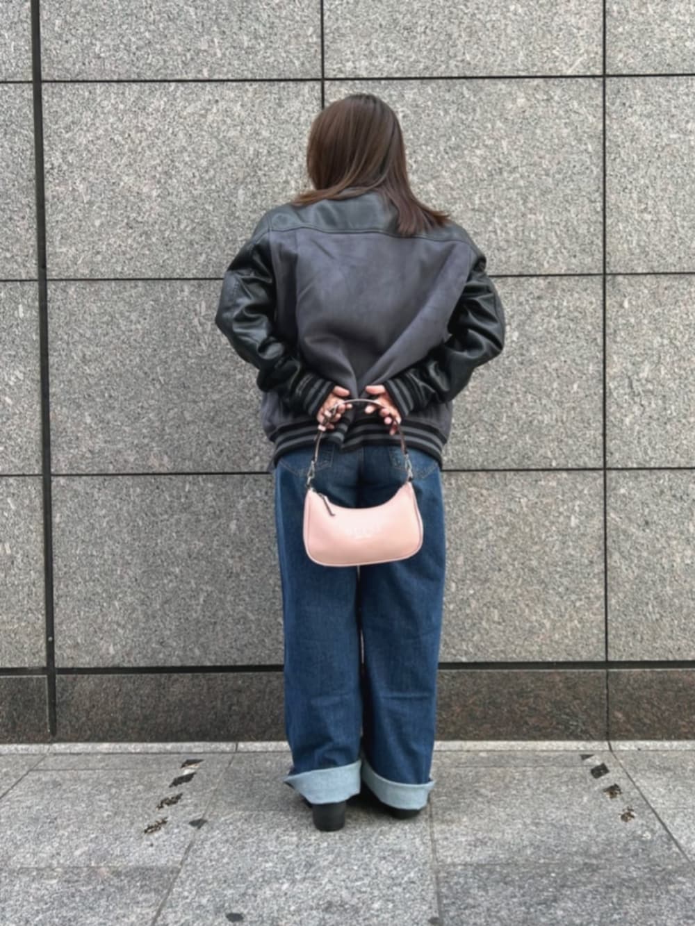 ブルー系のデニムパンツ、ブラック系のニット/セーター、グレー系のスタジャンを着用したレディースの秋コーディネートの2枚目の写真