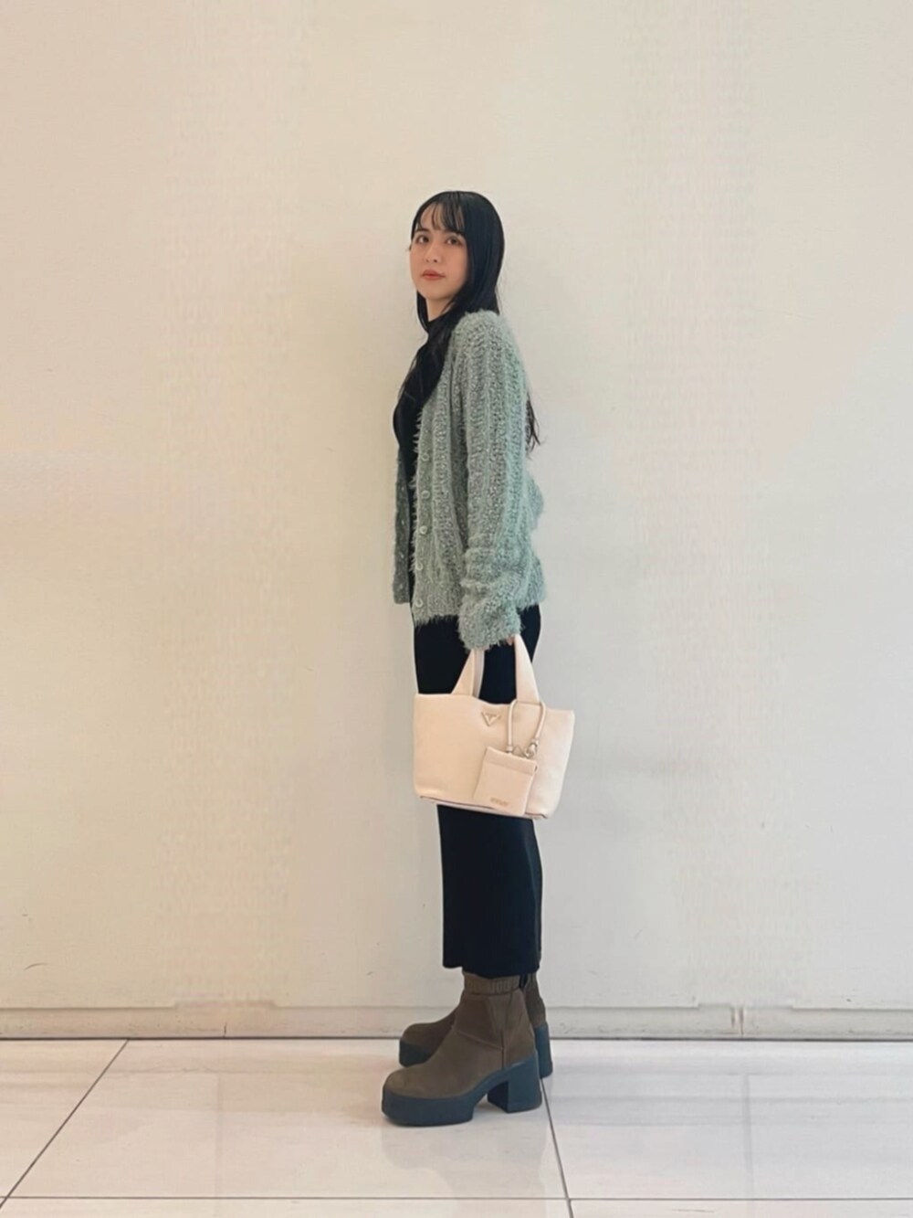 ブラック系のワンピース、グリーン系のカーディガン/ボレロ、ホワイト系のトートバッグを着用したレディースの秋コーディネートの3枚目の写真