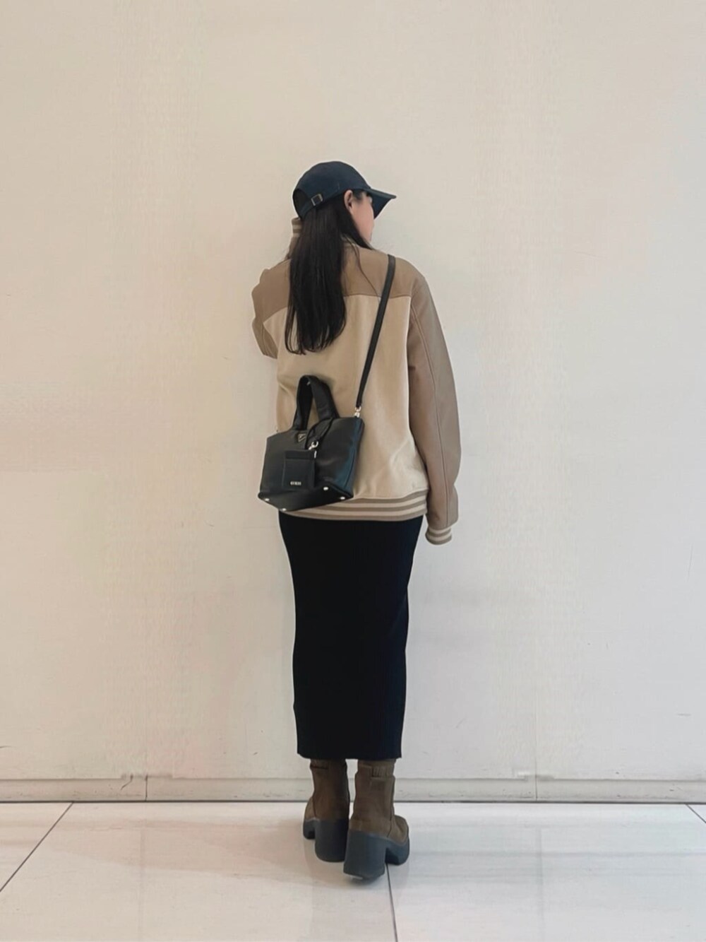 ブラック系のワンピース、ブラック系のトートバッグ、ベージュ系のスタジャンを着用したレディースの秋コーディネートの2枚目の写真