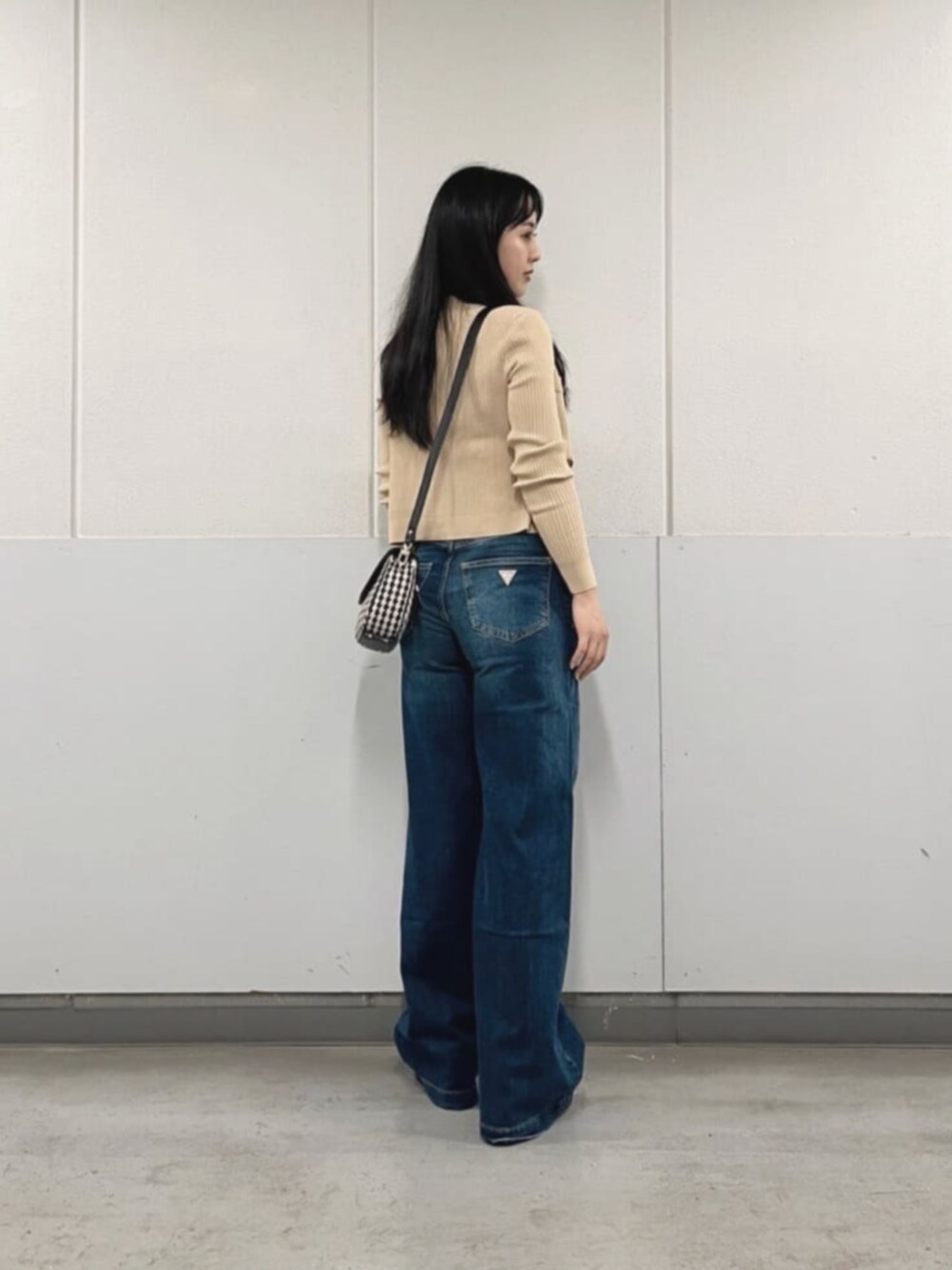 ベージュ系のカーディガン/ボレロ、ブルー系のデニムパンツ、ブラック系のショルダーバッグを着用したレディースの秋コーディネートの2枚目の写真