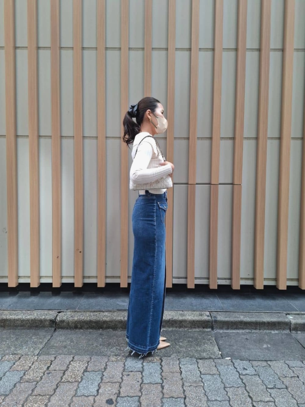 ブルー系のデニムスカート、ホワイト系のカーディガン/ボレロ、ホワイト系のハンドバッグを着用したレディースの秋コーディネートの3枚目の写真