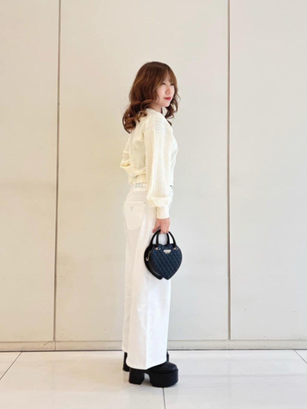 ホワイト系のデニムパンツ、ブラック系のショルダーバッグ、ベージュ系のカーディガン/ボレロを着用したレディースの冬コーディネートの3枚目の写真