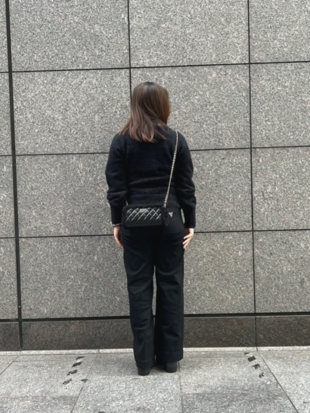 ブラック系のデニムパンツ、ブラック系のニット/セーター、ブラック系のショルダーバッグを着用したレディースの冬コーディネートの2枚目の写真