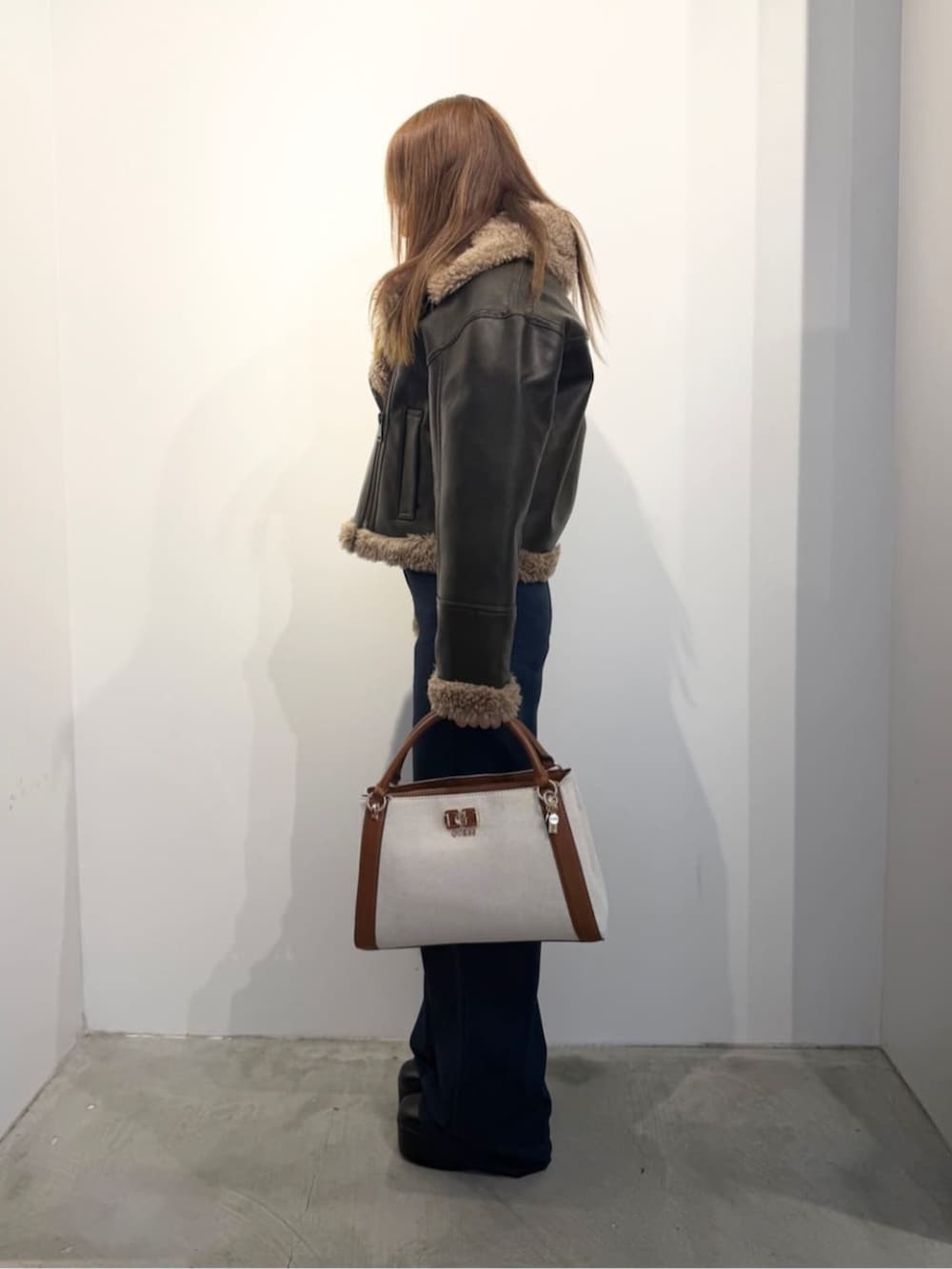 ホワイト系のニット/セーター、イエロー系のハンドバッグ、ブラウン系のライダースジャケットを着用したレディースの冬コーディネートの3枚目の写真