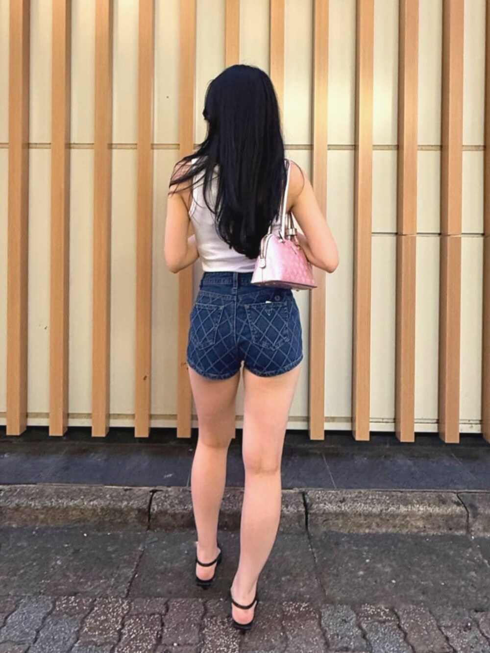 ピンク系のショルダーバッグ、ブルー系のデニムパンツ、ホワイト系のタンクトップを着用したレディースの夏コーディネートの2枚目の写真