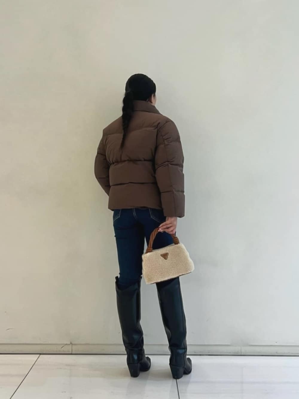 イエロー系のショルダーバッグ、ブルー系のデニムパンツ、ブラウン系のダウンジャケット/コートを着用したレディースの冬コーディネートの2枚目の写真