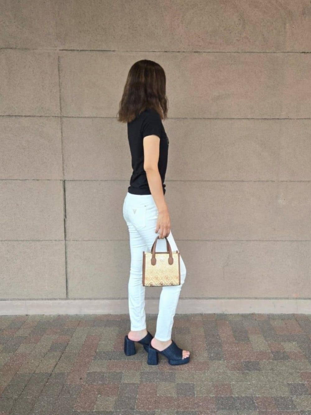 ブラウン系のショルダーバッグ、ホワイト系のデニムパンツ、ブラック系のTシャツ/カットソーを着用したレディースの秋コーディネートの3枚目の写真