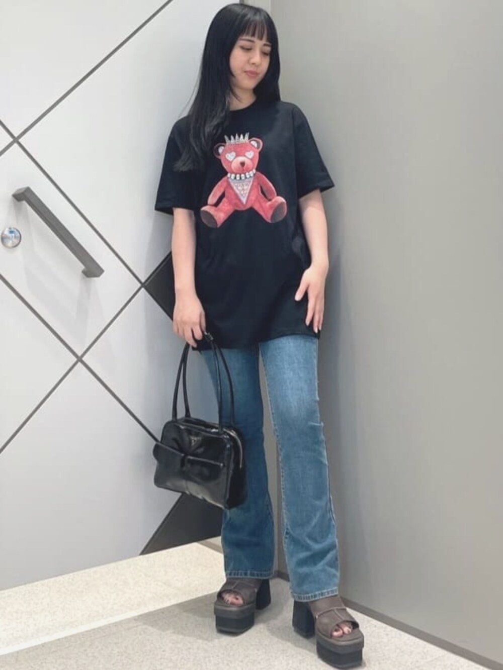 ブルー系のデニムパンツ、ブラック系のTシャツ/カットソー、ブラック系のショルダーバッグを着用したレディースの夏コーディネートの4枚目の写真