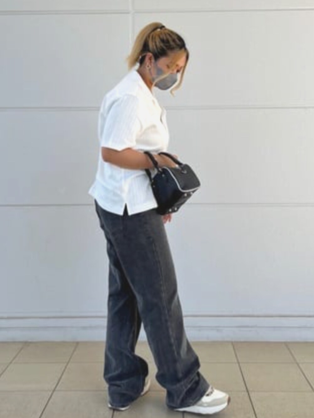 グレー系のデニムパンツ、ブラック系のハンドバッグ、ホワイト系のシャツ/ブラウスを着用したレディースの夏コーディネートの3枚目の写真