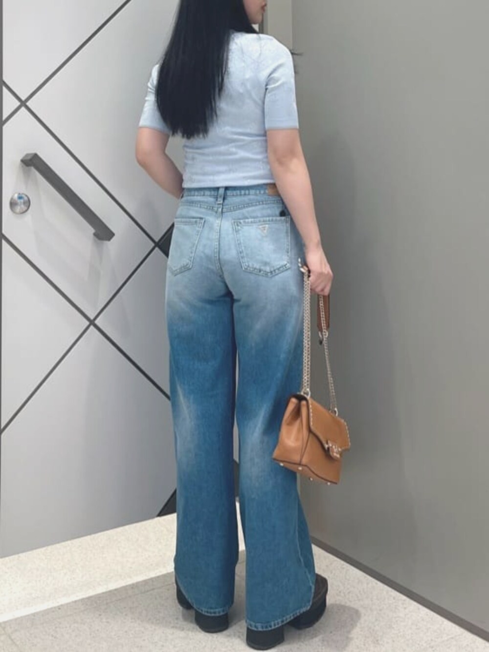 ブルー系のデニムパンツ、イエロー系のショルダーバッグ、ブルー系のニット/セーターを着用したレディースの夏コーディネートの2枚目の写真