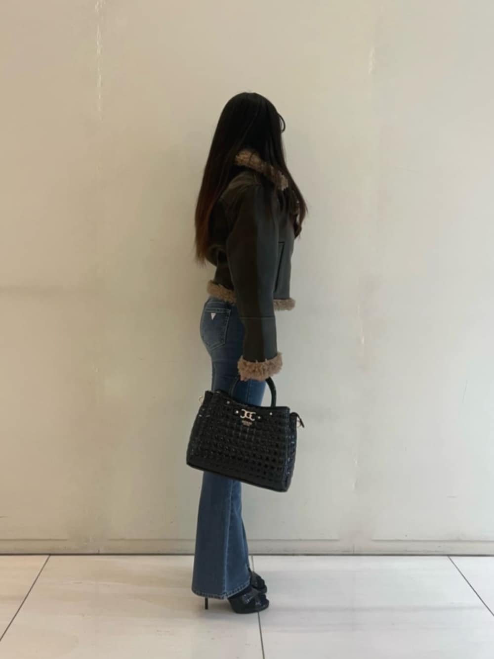 ブルー系のデニムパンツ、ブラック系のショルダーバッグ、ブラウン系のライダースジャケットを着用したレディースの冬コーディネートの3枚目の写真