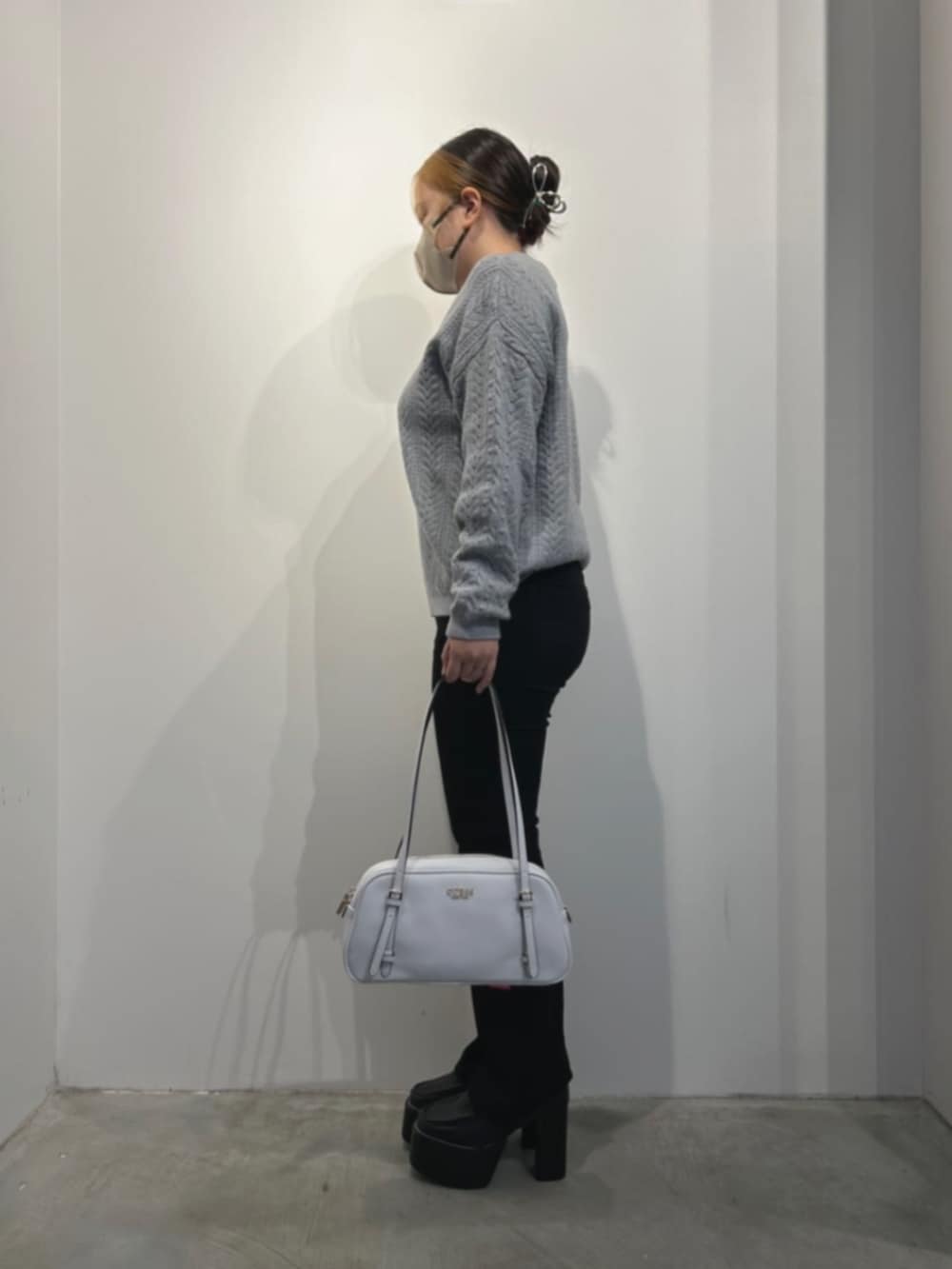 ホワイト系のショルダーバッグ、ブラック系のデニムパンツ、グレー系のニット/セーターを着用したレディースの冬コーディネートの3枚目の写真