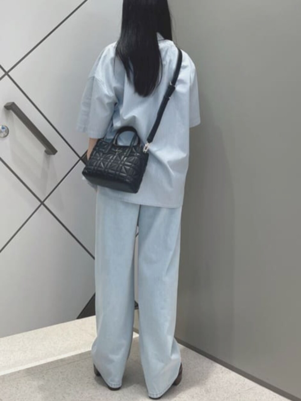 ブルー系のタンクトップ、ブルー系のデニムパンツ、ブラック系のショルダーバッグを着用したレディースの夏コーディネートの2枚目の写真