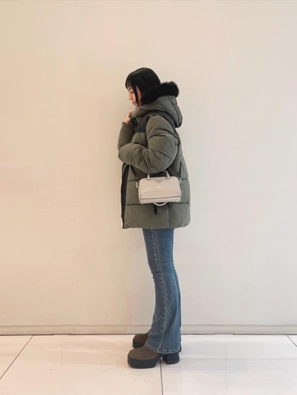 ブルー系のデニムパンツ、ホワイト系のニット/セーター、グリーン系のその他アウターを着用したレディースの冬コーディネートの3枚目の写真