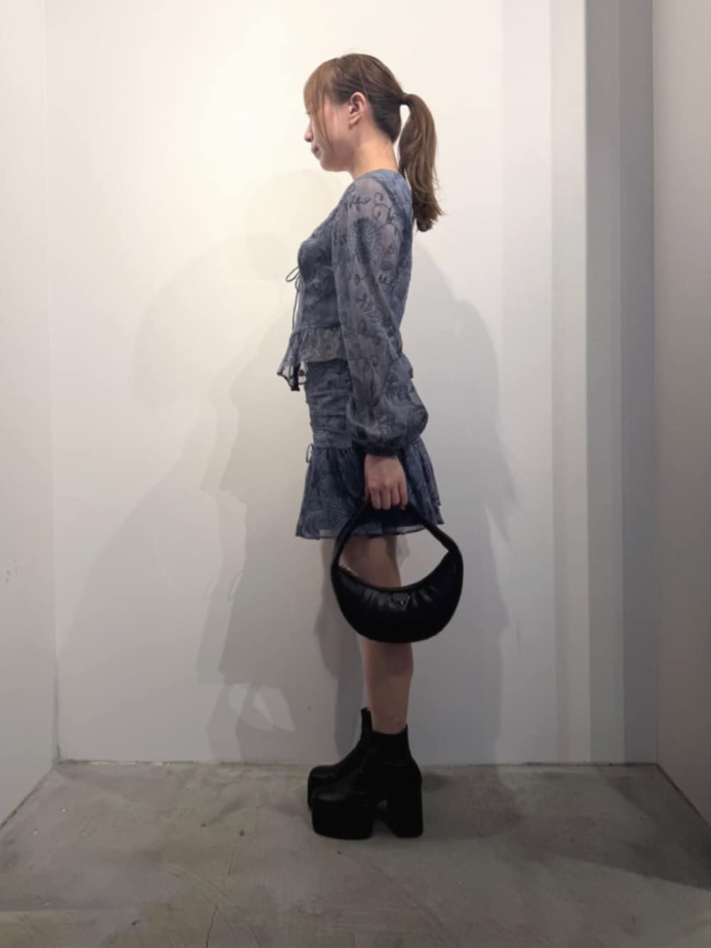 ブラック系のショルダーバッグ、ブルー系のシャツ/ブラウス、ブルー系のスカートを着用したレディースの冬コーディネートの3枚目の写真