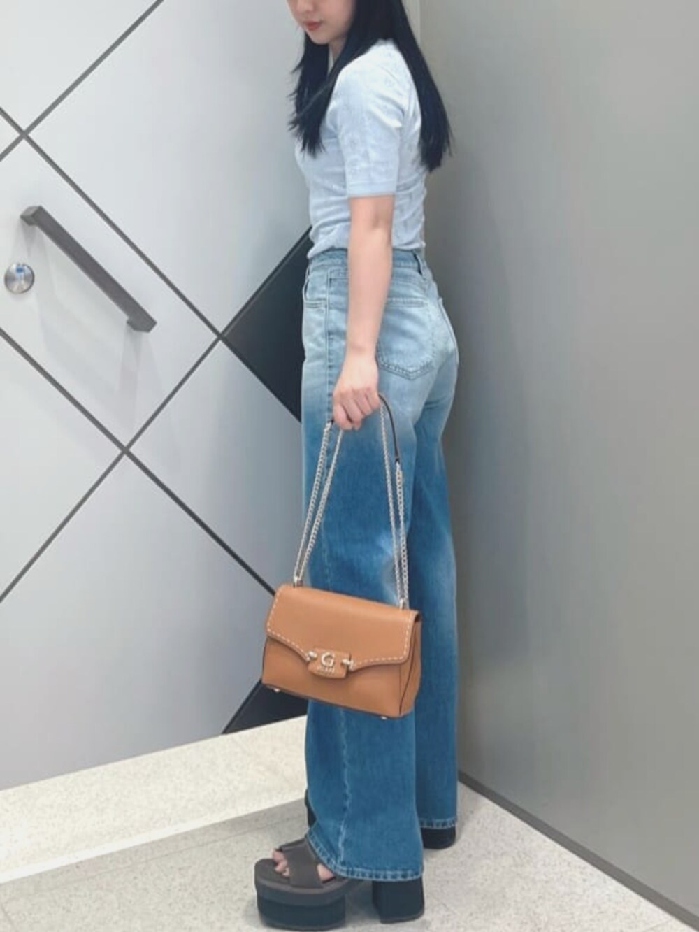 ブルー系のデニムパンツ、イエロー系のショルダーバッグ、ブルー系のニット/セーターを着用したレディースの夏コーディネートの3枚目の写真