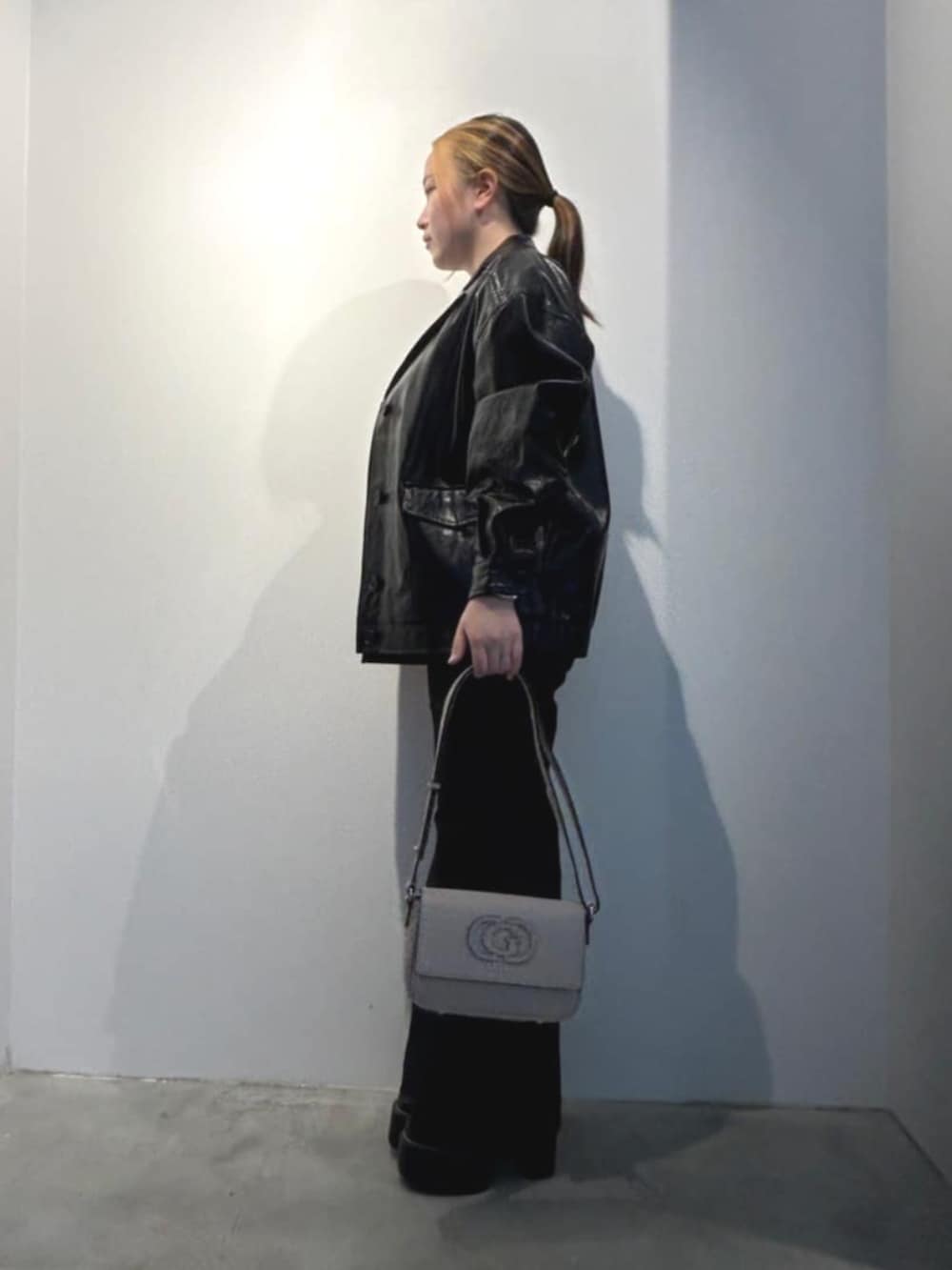 ブラック系のデニムパンツ、ベージュ系のショルダーバッグ、ブラック系のカバーオールを着用したレディースの春コーディネートの3枚目の写真