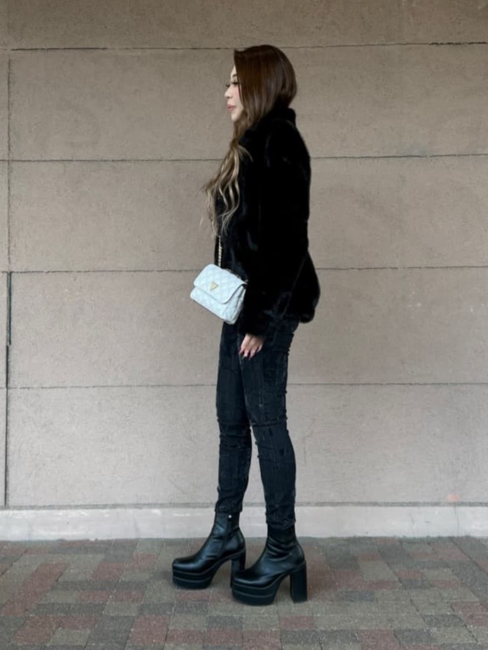 ブラック系のデニムパンツ、ホワイト系のショルダーバッグ、ベージュ系のTシャツ/カットソーを着用したレディースの春コーディネートの3枚目の写真