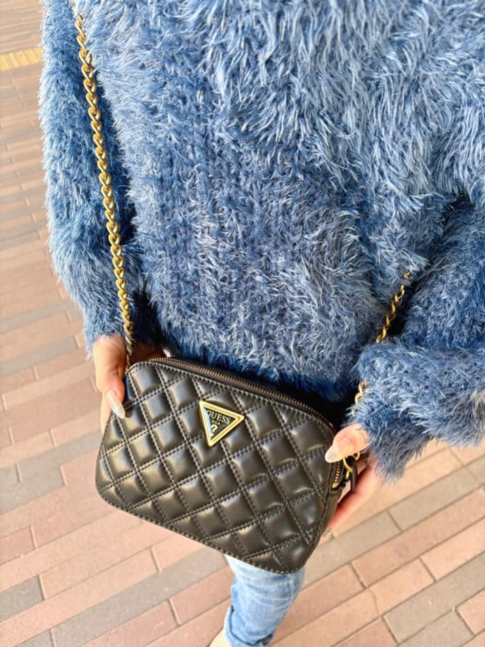 ブルー系のデニムパンツ、ブラック系のショルダーバッグ、ブルー系のニット/セーターを着用したレディースの冬コーディネートの4枚目の写真