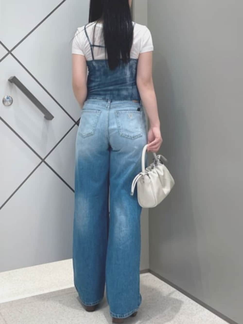 ベージュ系のショルダーバッグ、ホワイト系のその他トップス、ブルー系のデニムパンツを着用したレディースの夏コーディネートの3枚目の写真