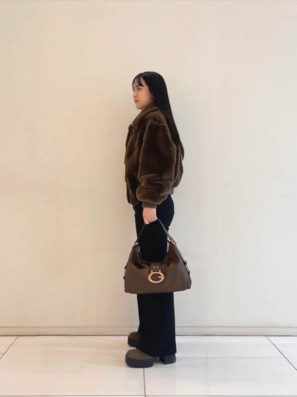 ブラック系のデニムパンツ、ブラウン系のショルダーバッグ、ブラック系のニット/セーターを着用したレディースの冬コーディネートの3枚目の写真