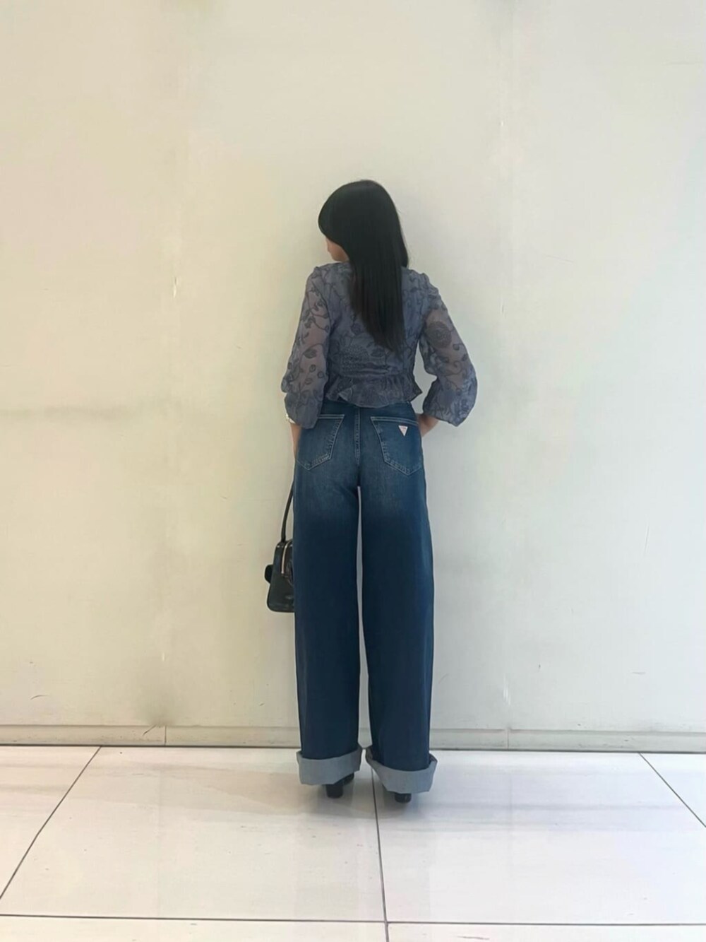 ブラック系のタンクトップ、ブラック系のショルダーバッグ、ブルー系のデニムパンツを着用したレディースの秋コーディネートの2枚目の写真