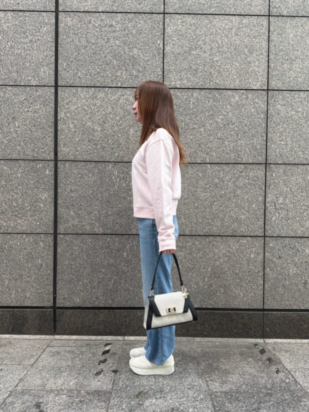 ブルー系のデニムパンツ、ブラック系のショルダーバッグ、ピンク系のスウェットを着用したレディースの冬コーディネートの3枚目の写真