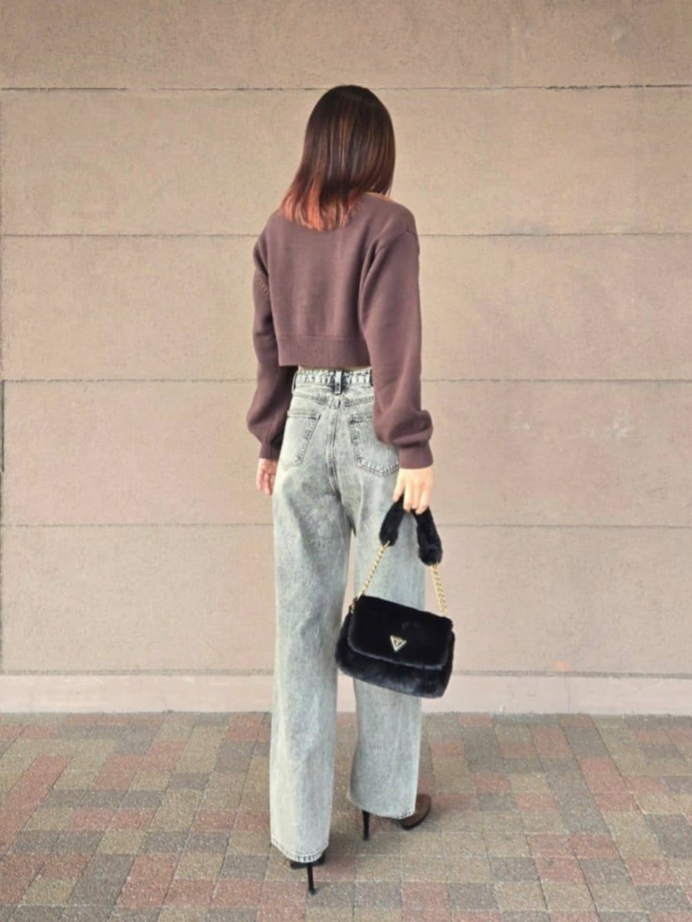 ブラック系のショルダーバッグ、グレー系のデニムパンツ、ブラウン系のニット/セーターを着用したレディースの冬コーディネートの2枚目の写真