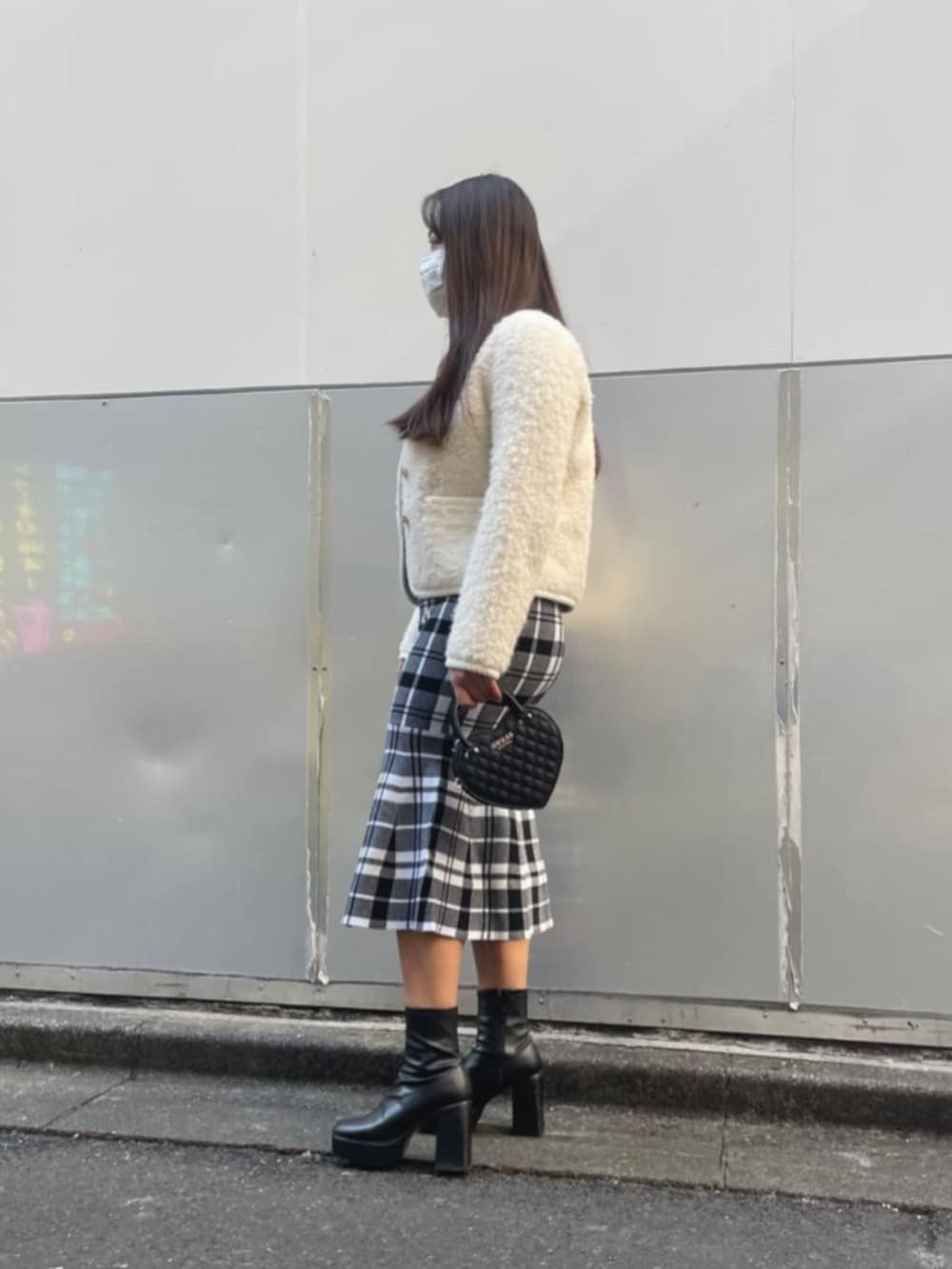 ブラック系のワンピース、ブラック系のショルダーバッグ、ホワイト系のノーカラージャケットを着用したレディースの冬コーディネートの3枚目の写真