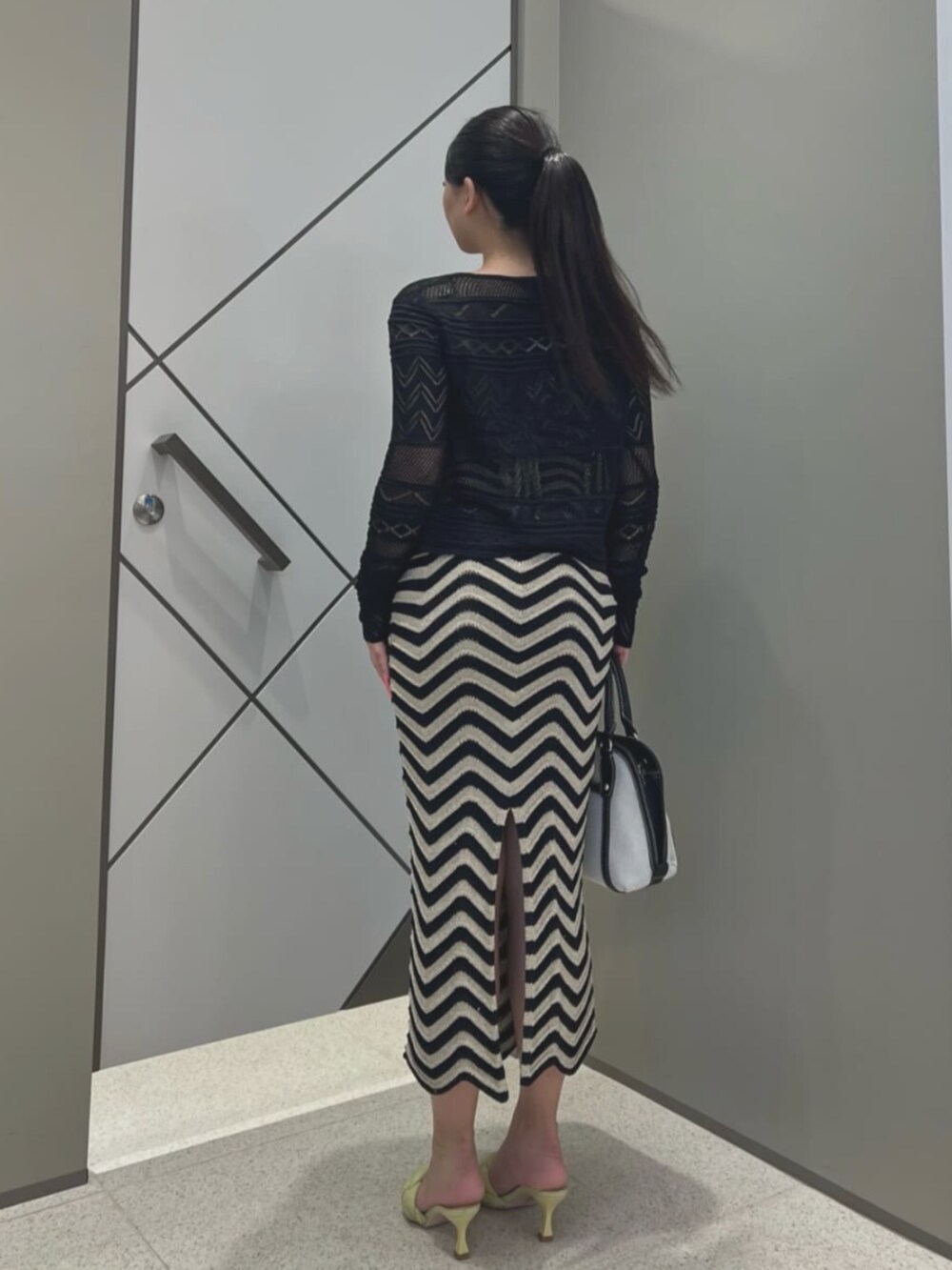 ブラック系のショルダーバッグ、ブラック系のカーディガン/ボレロ、ブラック系のワンピースを着用したレディースの夏コーディネートの2枚目の写真