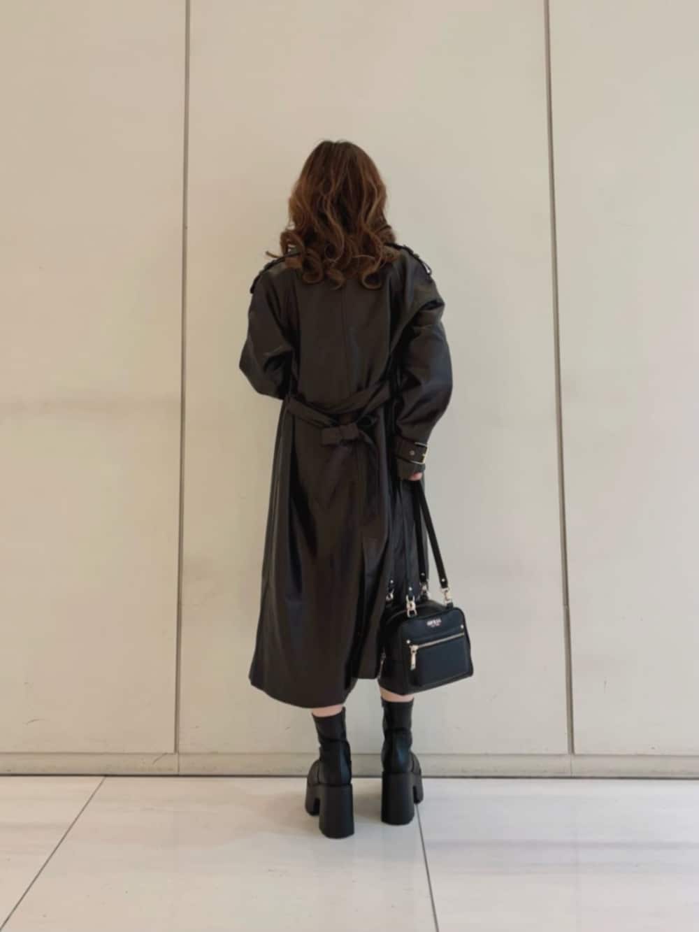 ブラウン系のワンピース、ブラウン系のトレンチコート、ブラック系のショルダーバッグを着用したレディースの冬コーディネートの2枚目の写真