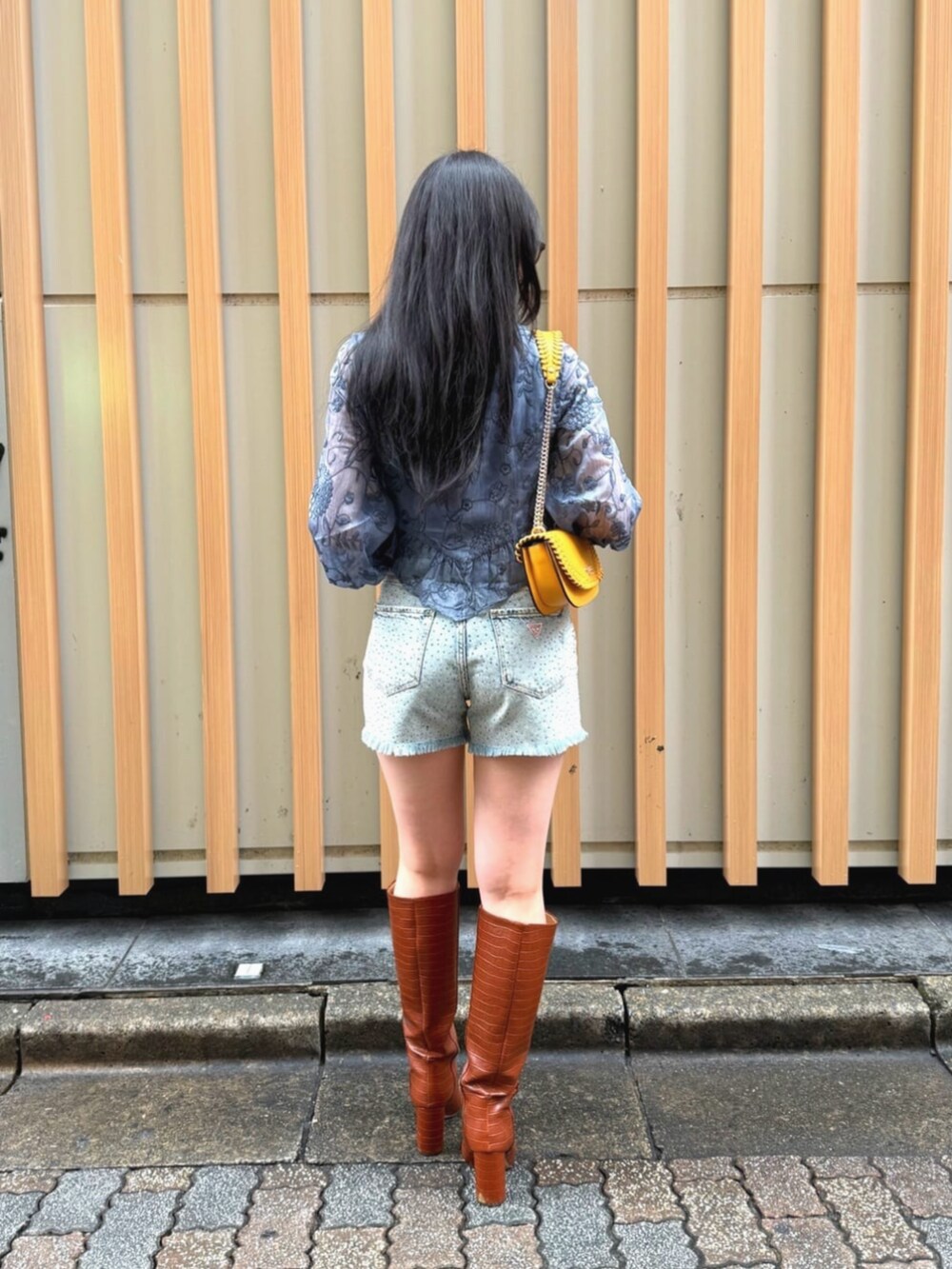 ブルー系のデニムパンツ、ブルー系のシャツ/ブラウス、オレンジ系のショルダーバッグを着用したレディースの秋コーディネートの2枚目の写真