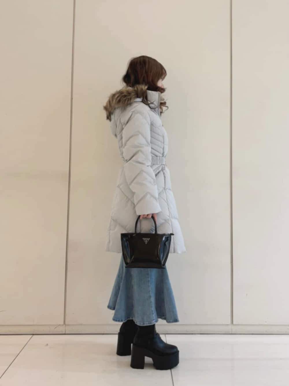 グレー系のダウンジャケット/コート、ブルー系のデニムスカート、ブラック系のトートバッグを着用したレディースの冬コーディネートの3枚目の写真