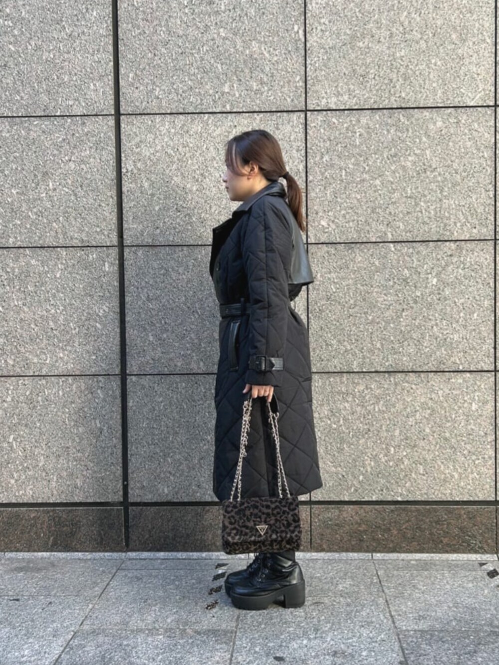 ブルー系のデニムパンツ、ブラック系のカーディガン/ボレロ、ブラック系のトレンチコートを着用したレディースの秋コーディネートの3枚目の写真