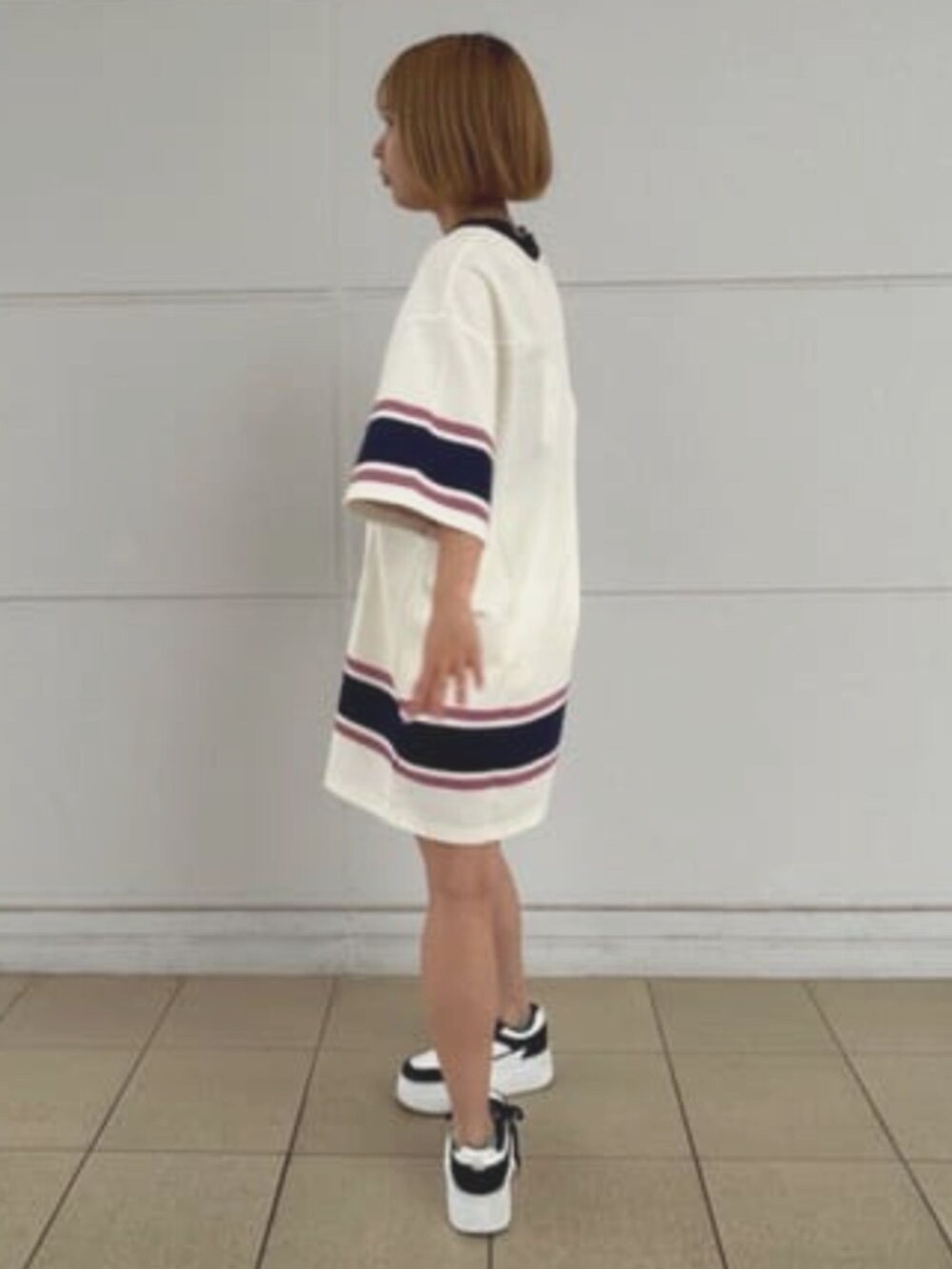 ブラック系のハンドバッグ、ホワイト系のワンピースを着用したレディースの夏コーディネートの3枚目の写真