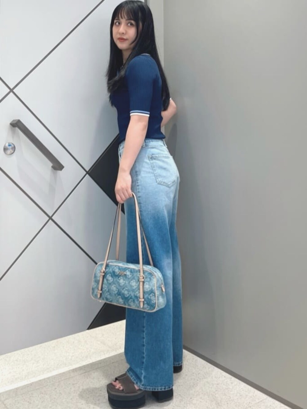 ブルー系のショルダーバッグ、ブルー系のポロシャツ、ブルー系のデニムパンツを着用したレディースの夏コーディネートの3枚目の写真