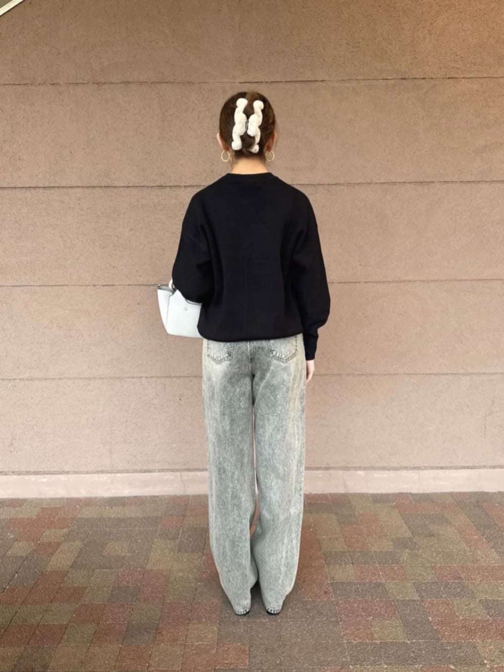 ホワイト系のショルダーバッグ、グレー系のデニムパンツ、ブラック系のニット/セーターを着用したレディースの冬コーディネートの2枚目の写真