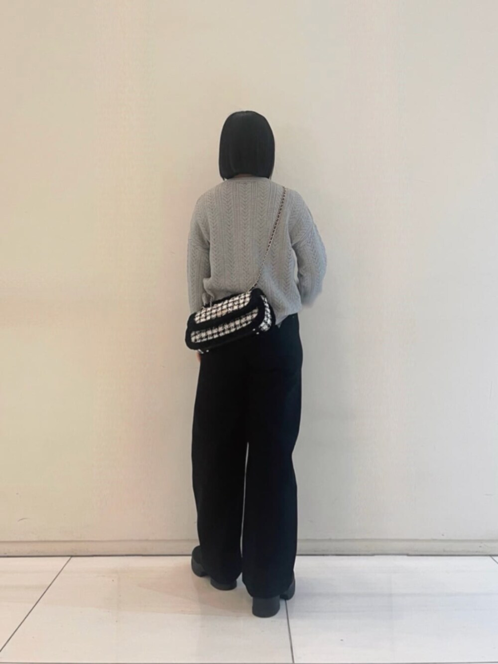 ブラック系のデニムパンツ、グレー系のニット/セーター、ブラック系のショルダーバッグを着用したレディースの冬コーディネートの2枚目の写真