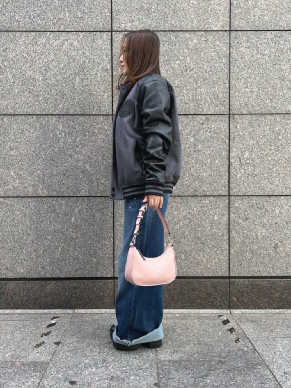 ブルー系のデニムパンツ、ブラック系のニット/セーター、グレー系のスタジャンを着用したレディースの秋コーディネートの3枚目の写真