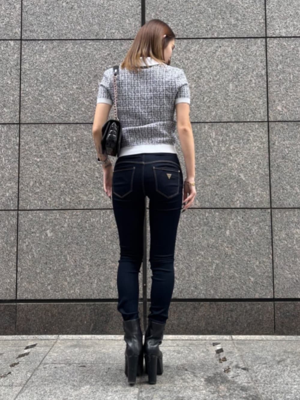 ブルー系のデニムパンツ、ブラック系のショルダーバッグ、ブラック系のニット/セーターを着用したレディースの春コーディネートの3枚目の写真